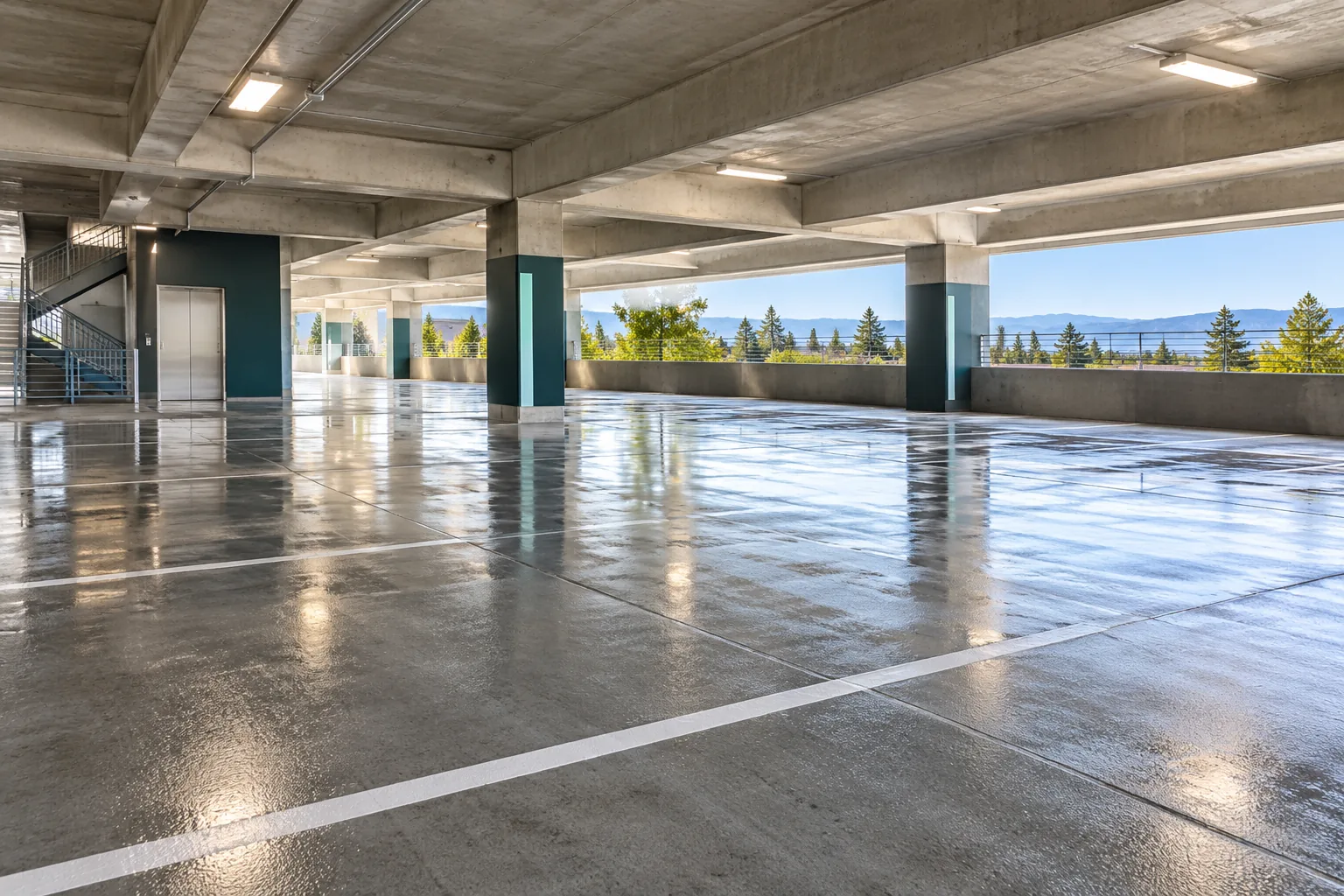 Empty parking garage deck with freshly washed concrete, painted stall lines and overhead lights